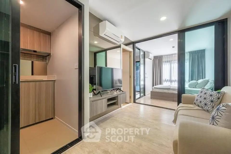 Modern apartment interior with open living room and bedroom, featuring sleek design and natural light.