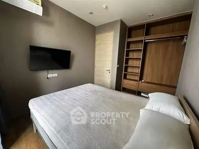 Modern bedroom with built-in wardrobe and wall-mounted TV in a cozy apartment.