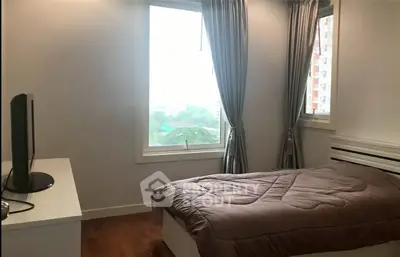 Cozy bedroom with large window and modern decor in urban apartment.