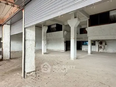Spacious industrial-style open area with concrete pillars and high ceilings.
