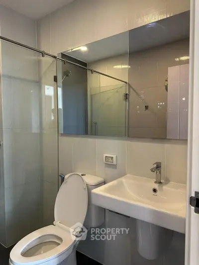 Modern bathroom with glass shower and sleek fixtures in contemporary apartment.
