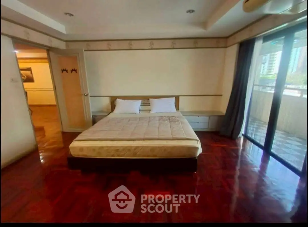 Spacious bedroom with large windows and balcony access in modern apartment.