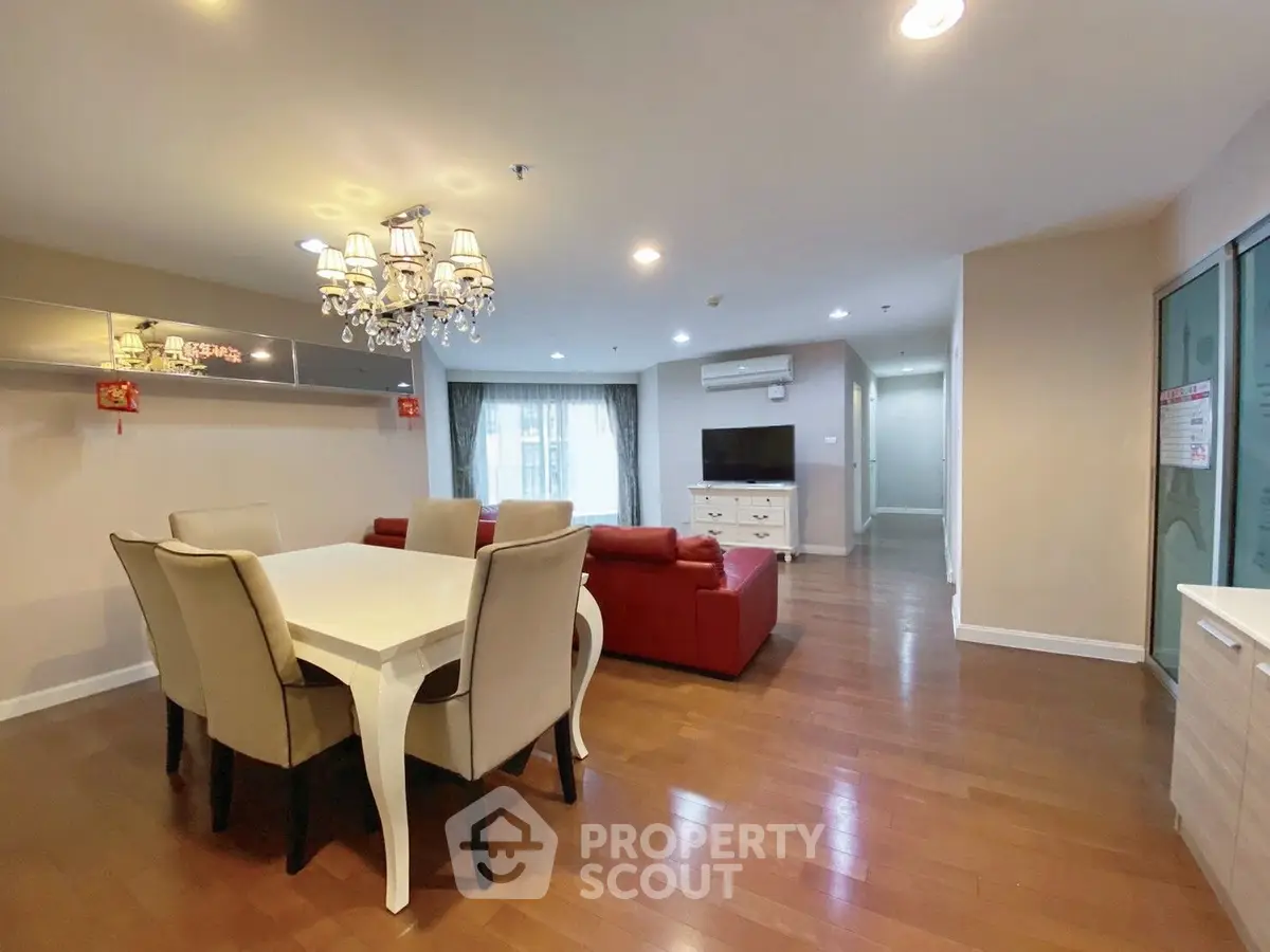 Spacious living room with elegant chandelier and modern furniture in a stylish apartment.