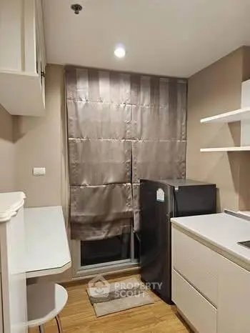 Modern compact kitchen with sleek cabinetry and a small fridge, perfect for urban living.