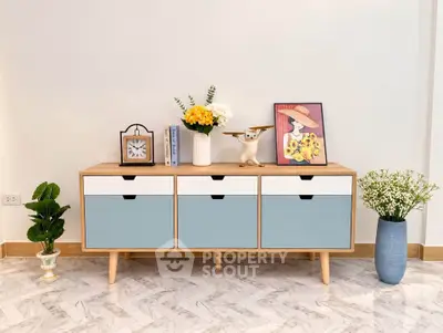 Stylish modern sideboard with decorative plants and art in a chic living room setting.