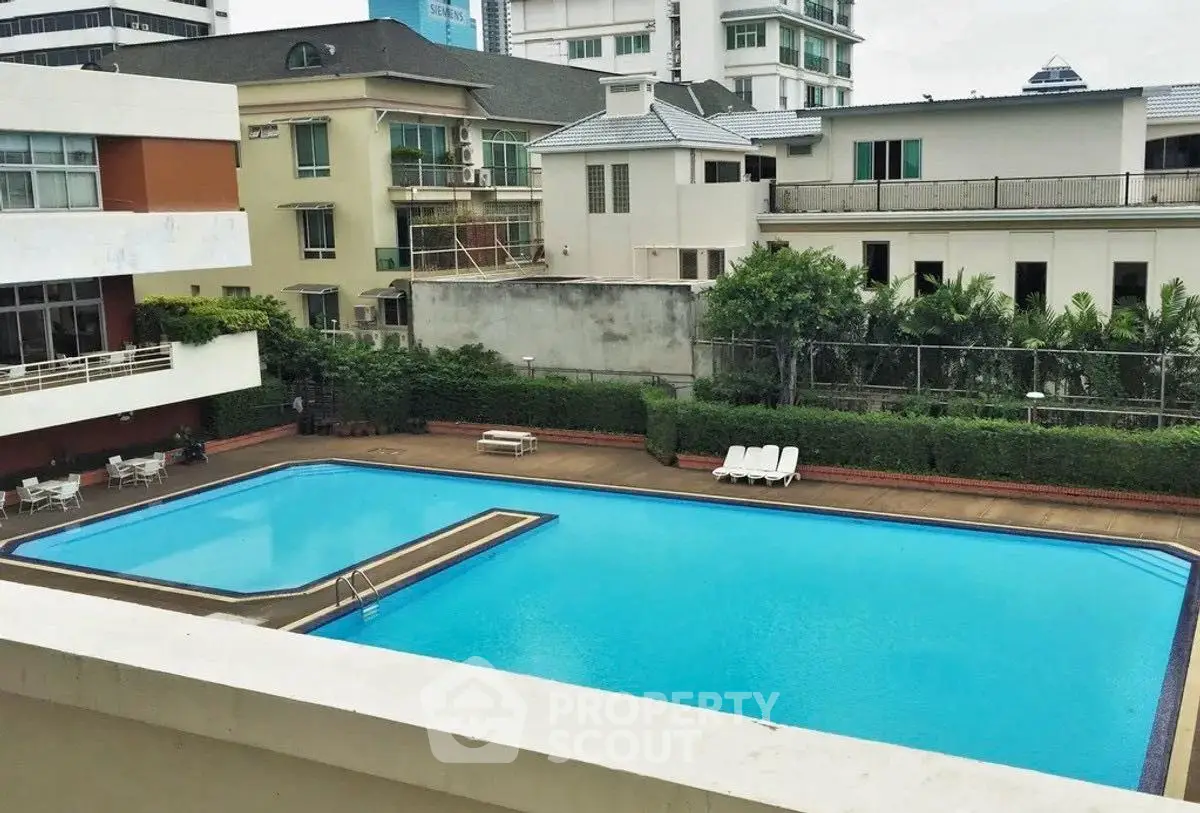 Luxurious residential complex with pristine swimming pool and lush greenery in urban setting.