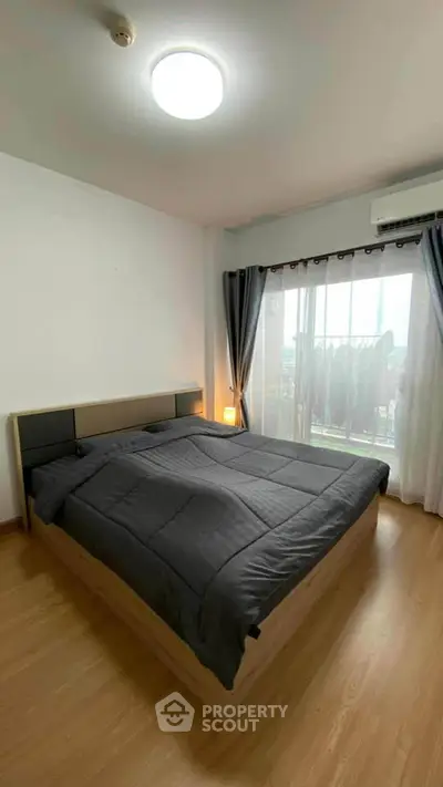 Spacious bedroom with modern decor and large window offering natural light.