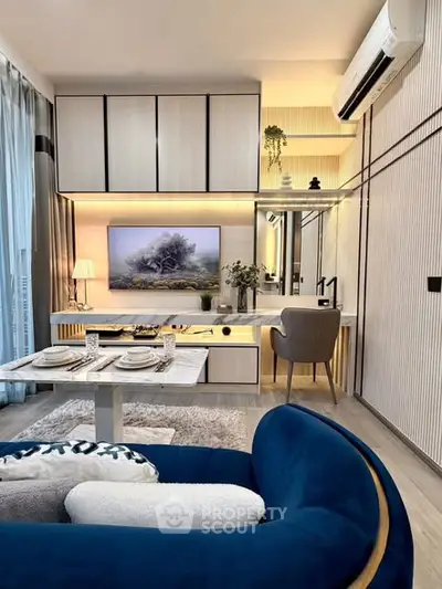 Modern living room with stylish furniture and elegant decor, featuring a cozy blue sofa and a sleek dining area.