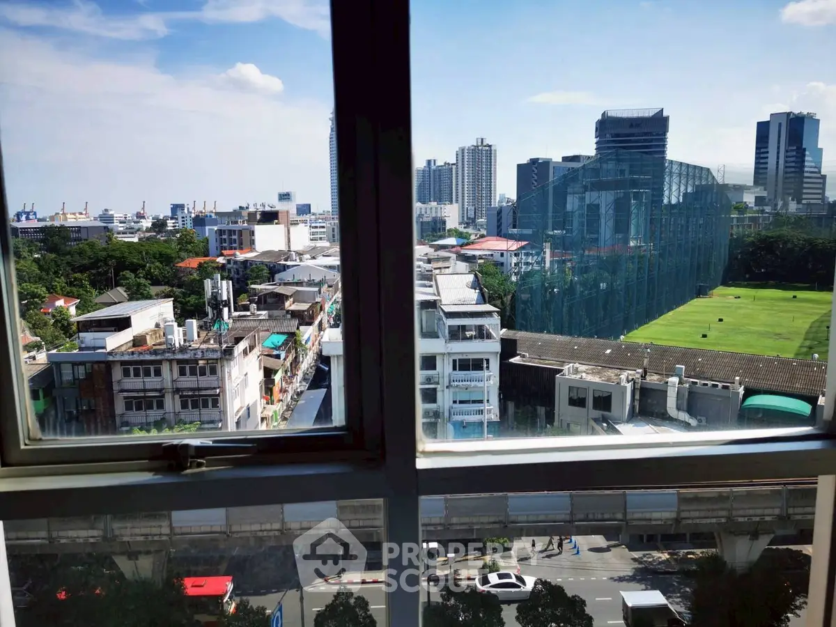 Stunning cityscape view from high-rise window showcasing urban skyline and lush greenery.