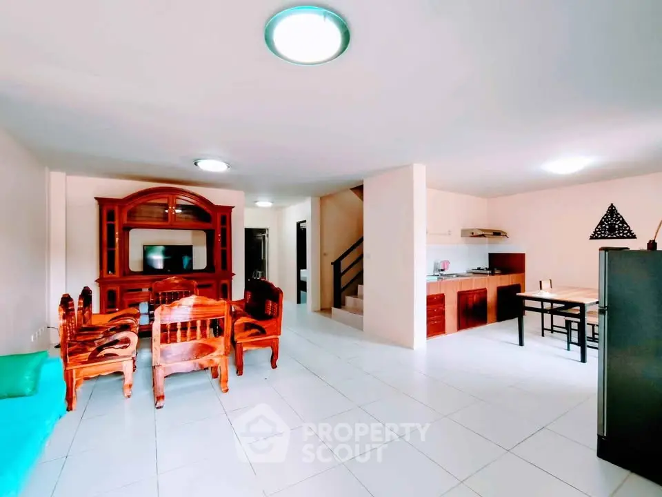 Spacious open-plan living room with elegant wooden furniture and modern kitchen area.
