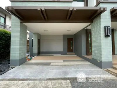 Modern residential building entrance with covered parking and sleek architectural design.