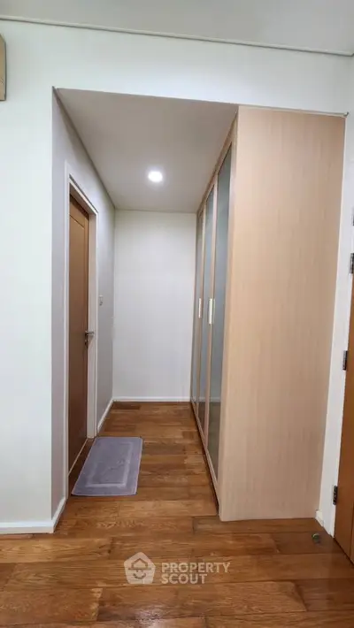 Spacious hallway with wooden flooring and built-in wardrobe in modern apartment.