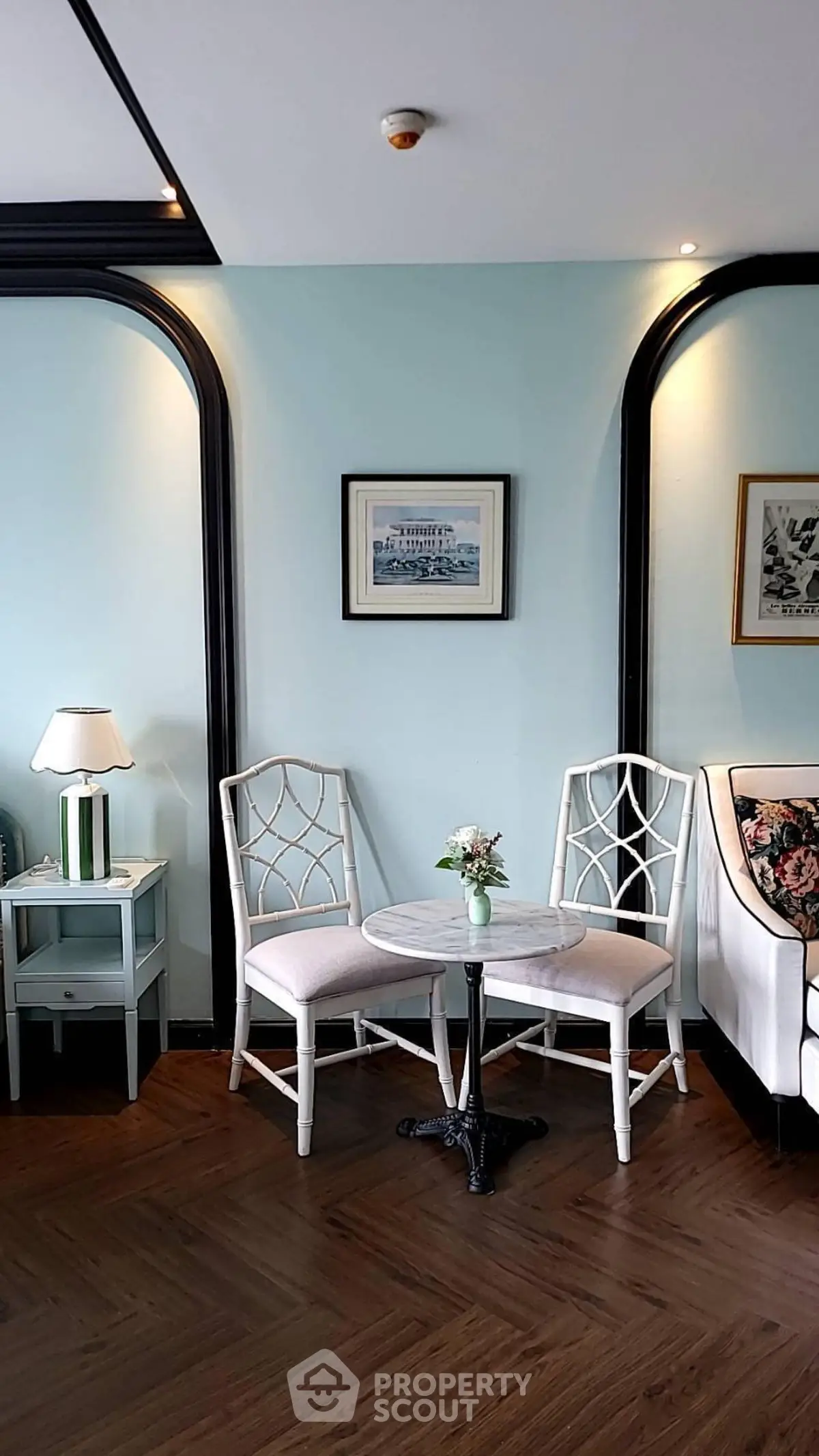 Charming living room with elegant chairs and table, featuring stylish decor and wooden flooring.