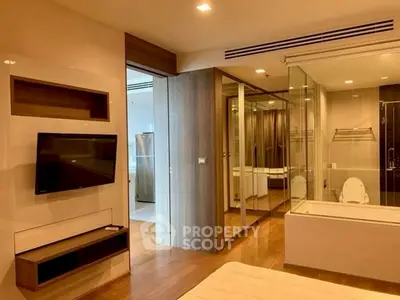 Modern bedroom with glass-walled bathroom and sleek wooden flooring.