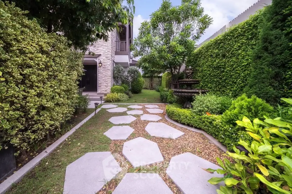 Charming garden pathway with lush greenery and elegant stone design in a serene residential setting.