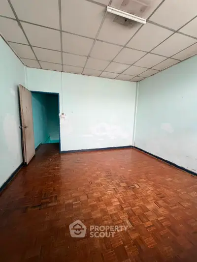 Spacious empty room with parquet flooring and light blue walls, ideal for customization.