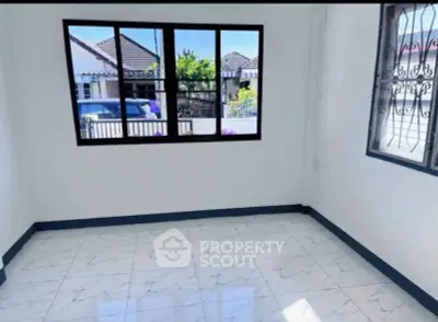 Bright empty room with large window and tiled floor, offering a view of suburban houses.