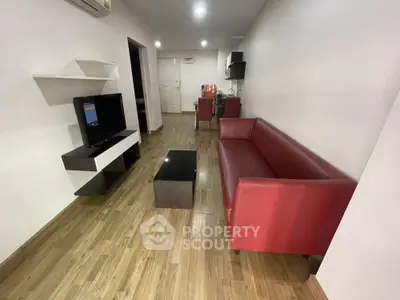 Modern living room with red sofa and flat-screen TV, wooden flooring, and sleek decor.