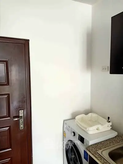 Compact kitchen corner with washing machine and sink, ideal for efficient apartment living.
