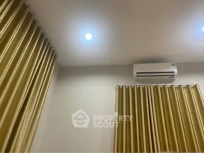 Modern interior with elegant gold curtains and air conditioning unit, perfect for comfortable living.