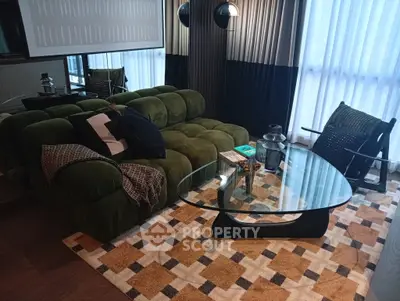 Stylish living room with plush green sofa, modern glass coffee table, and chic decor accents.