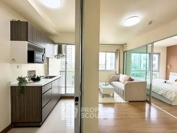Modern open-layout apartment with sleek kitchen and cozy living area, featuring large windows for natural light.