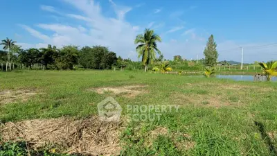 Expansive green land with palm trees and serene pond, perfect for development or agriculture.