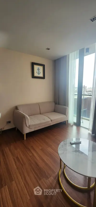 Modern living room with cozy sofa and large window offering natural light and city view.