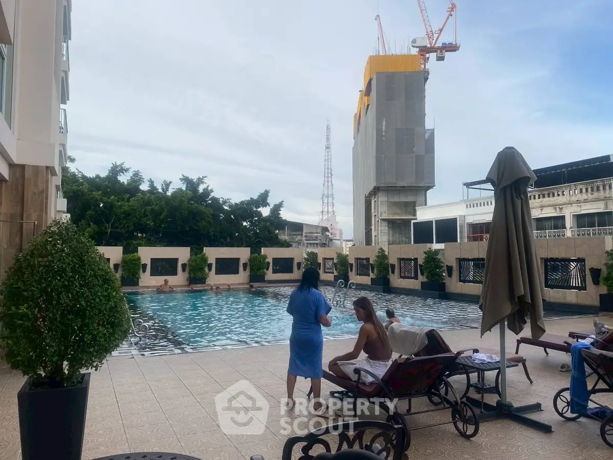 Luxurious apartment pool area with sun loungers and city views, perfect for relaxation and leisure.