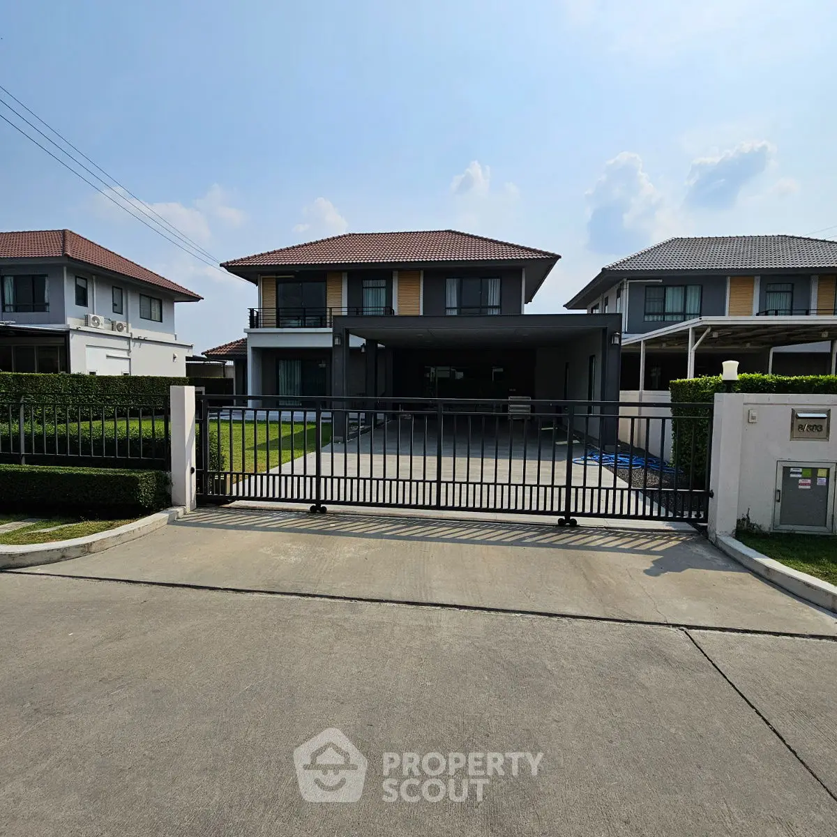 Modern two-story house with gated driveway and manicured lawn in a suburban neighborhood.