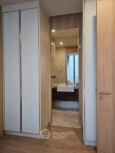 Modern interior with sleek bathroom and stylish wardrobe, featuring elegant wood and marble finishes.
