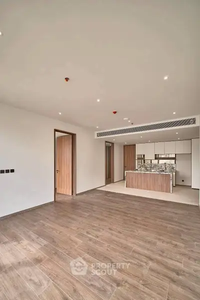 Spacious modern living room with open kitchen and wooden flooring in a luxury apartment.