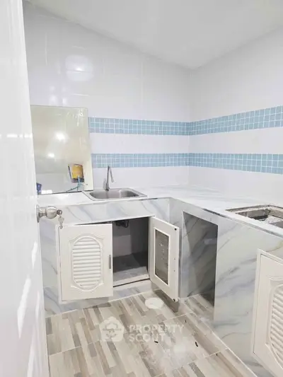 Modern kitchen with marble countertops and blue tile accents