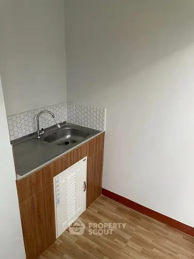 Compact kitchen area with modern sink and wooden cabinetry