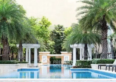 Luxurious outdoor pool area with palm trees and elegant columns in a serene residential setting.