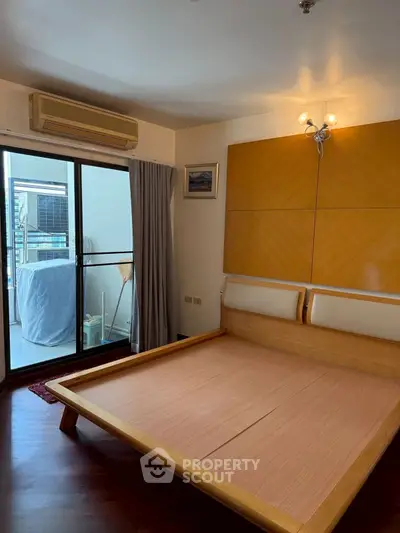 Spacious bedroom with wooden bed frame and balcony access in modern apartment