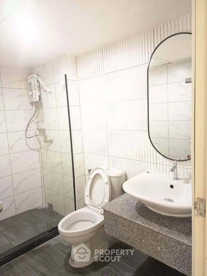 Modern bathroom with sleek fixtures and glass shower enclosure in a stylish apartment.
