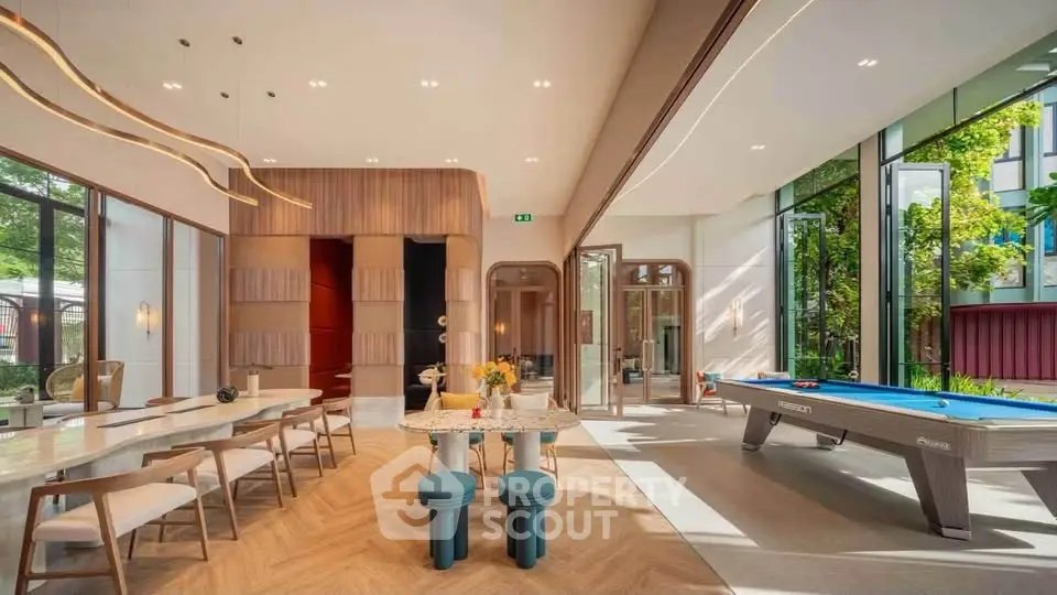 Luxurious modern living room with pool table and elegant dining area, featuring floor-to-ceiling windows and stylish decor.