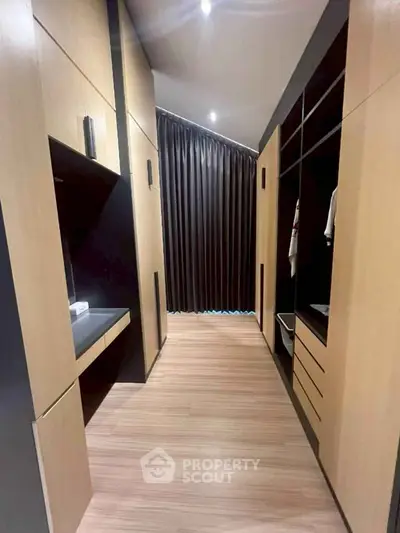 Spacious walk-in closet with modern wooden cabinetry and elegant lighting.