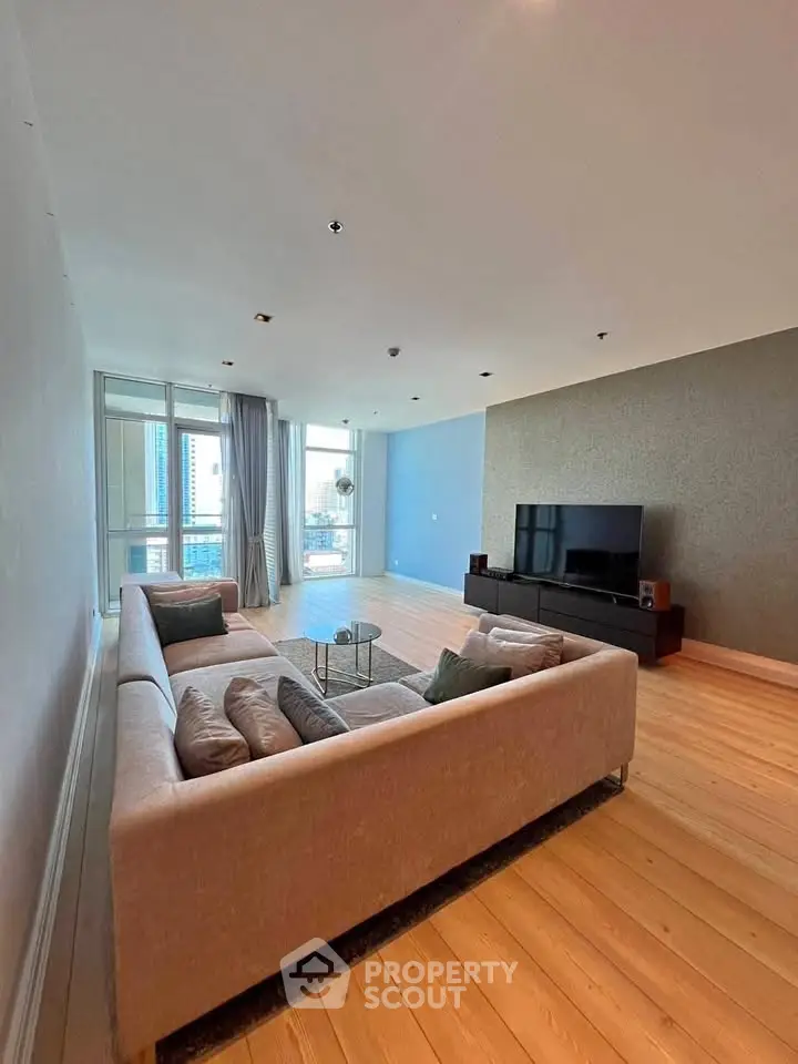 Spacious modern living room with large windows and stylish furniture in a high-rise apartment.