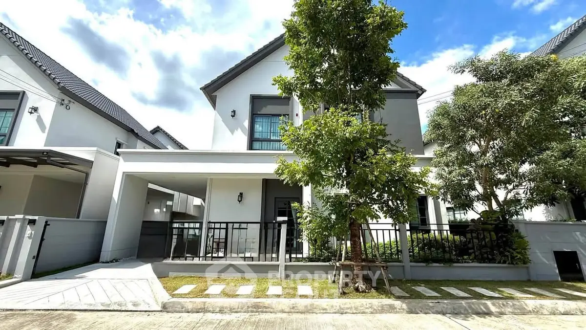 Modern two-story house with sleek design and lush greenery in a serene neighborhood.