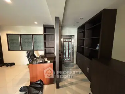 Spacious home office with built-in dark wood shelves and modern desk setup.