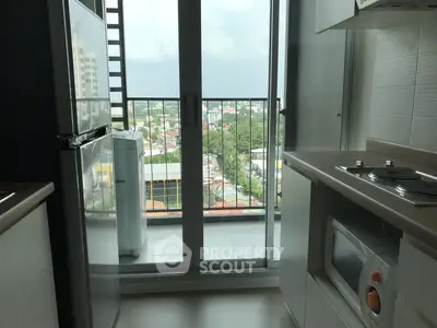 Modern kitchen with balcony view and sleek appliances in high-rise apartment.