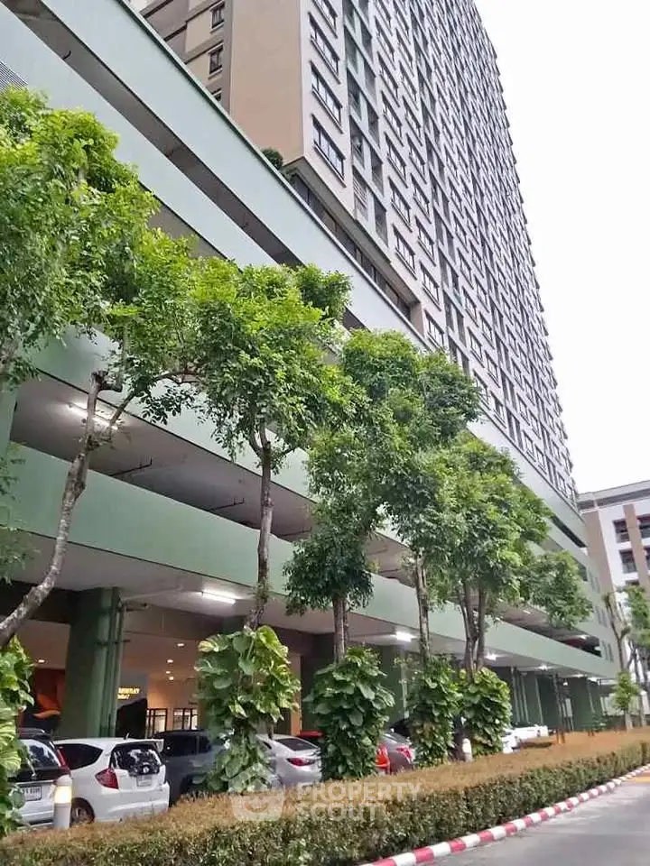 Modern high-rise building with lush greenery and parking area, ideal urban living.