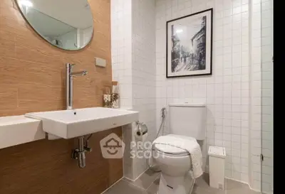 Modern bathroom with stylish decor and wall art, featuring a sleek sink and toilet.