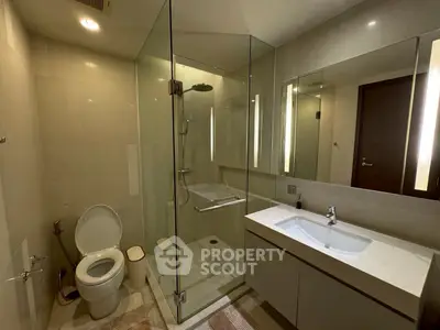 Modern bathroom with glass shower and sleek fixtures in luxury apartment.