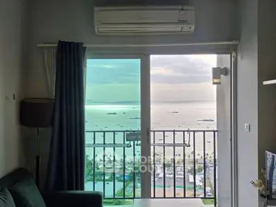 Stunning ocean view from a modern high-rise apartment living room with balcony.