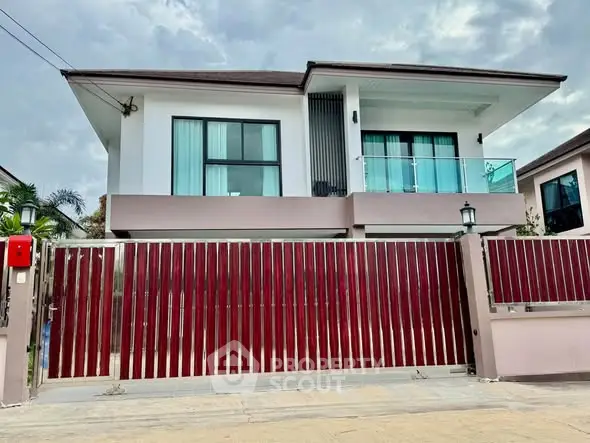 Modern two-story house with sleek design and large windows, featuring a stylish red gate.