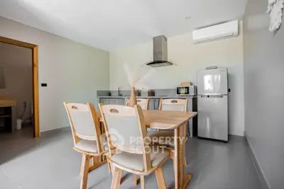 Modern kitchen with dining area, featuring sleek appliances and minimalist design.