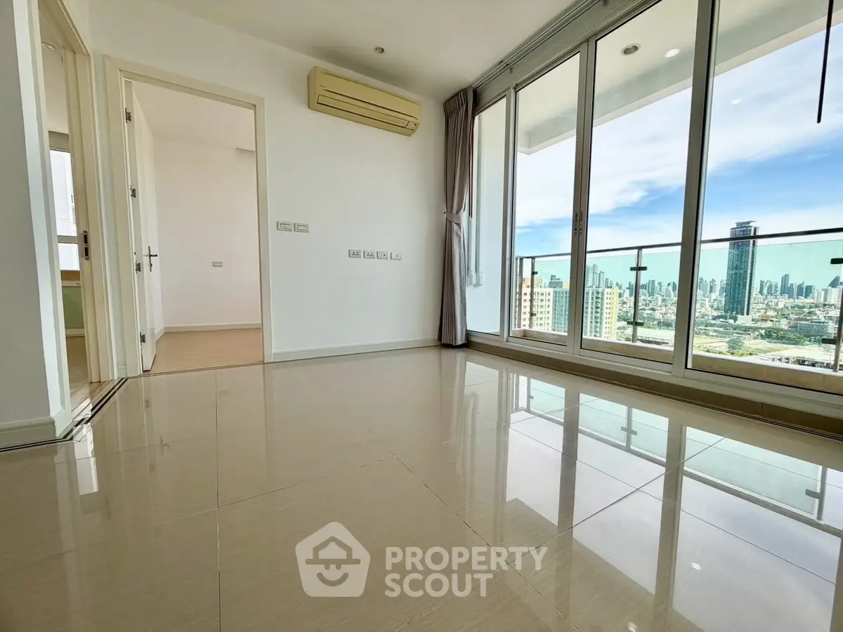 Spacious modern living room with city view and large windows in high-rise apartment.